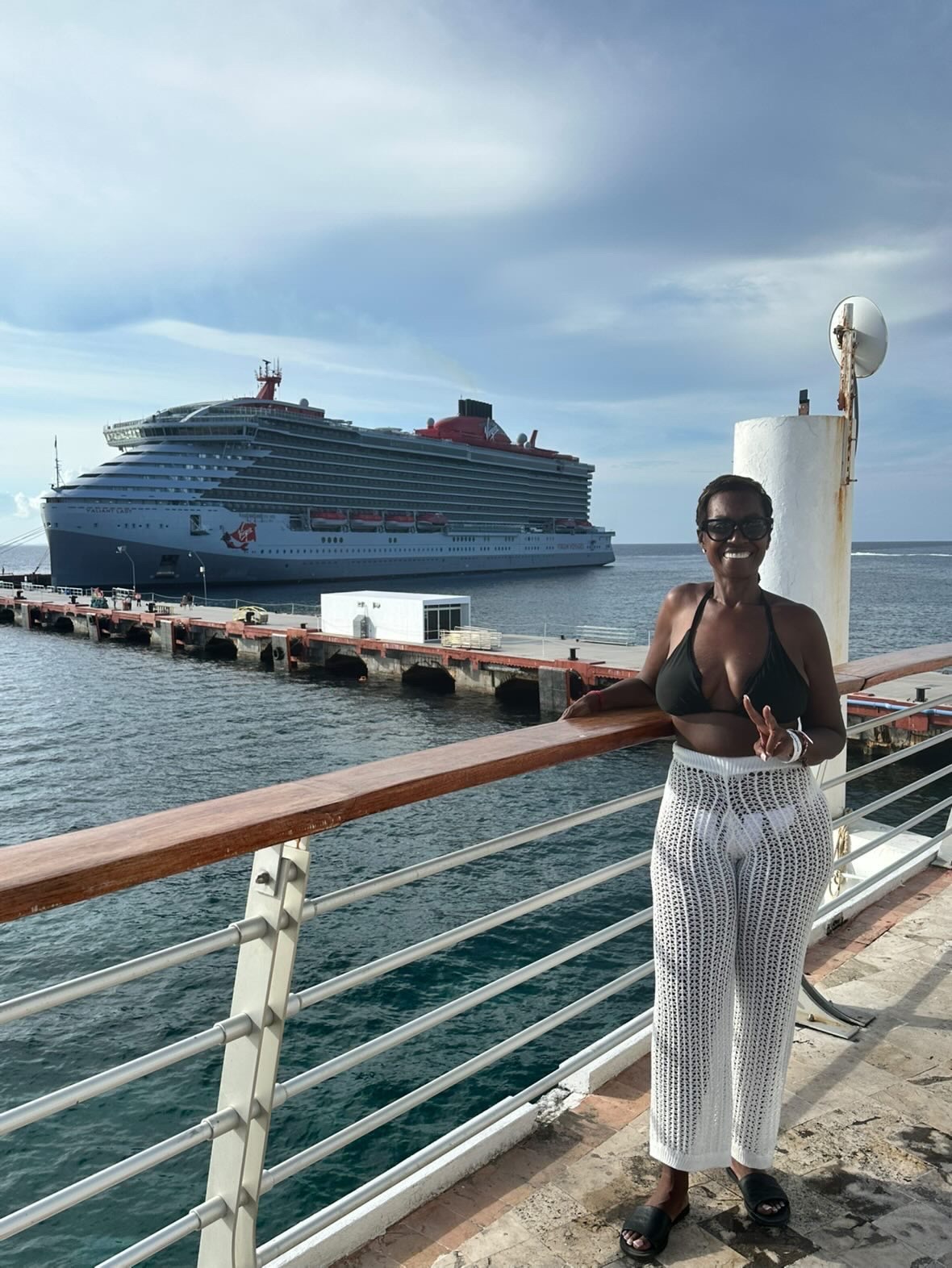 Arliee on the pier with a Virgin Voyages ship behind her